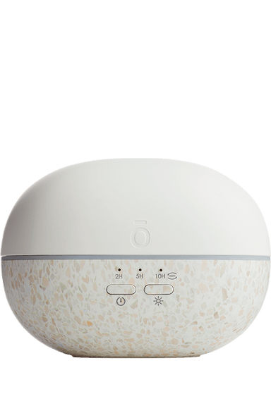A modern essential oil diffuser with a matte white top dome and a terrazzo-patterned lower base in white, beige, and light pink, featuring control buttons on the front.
