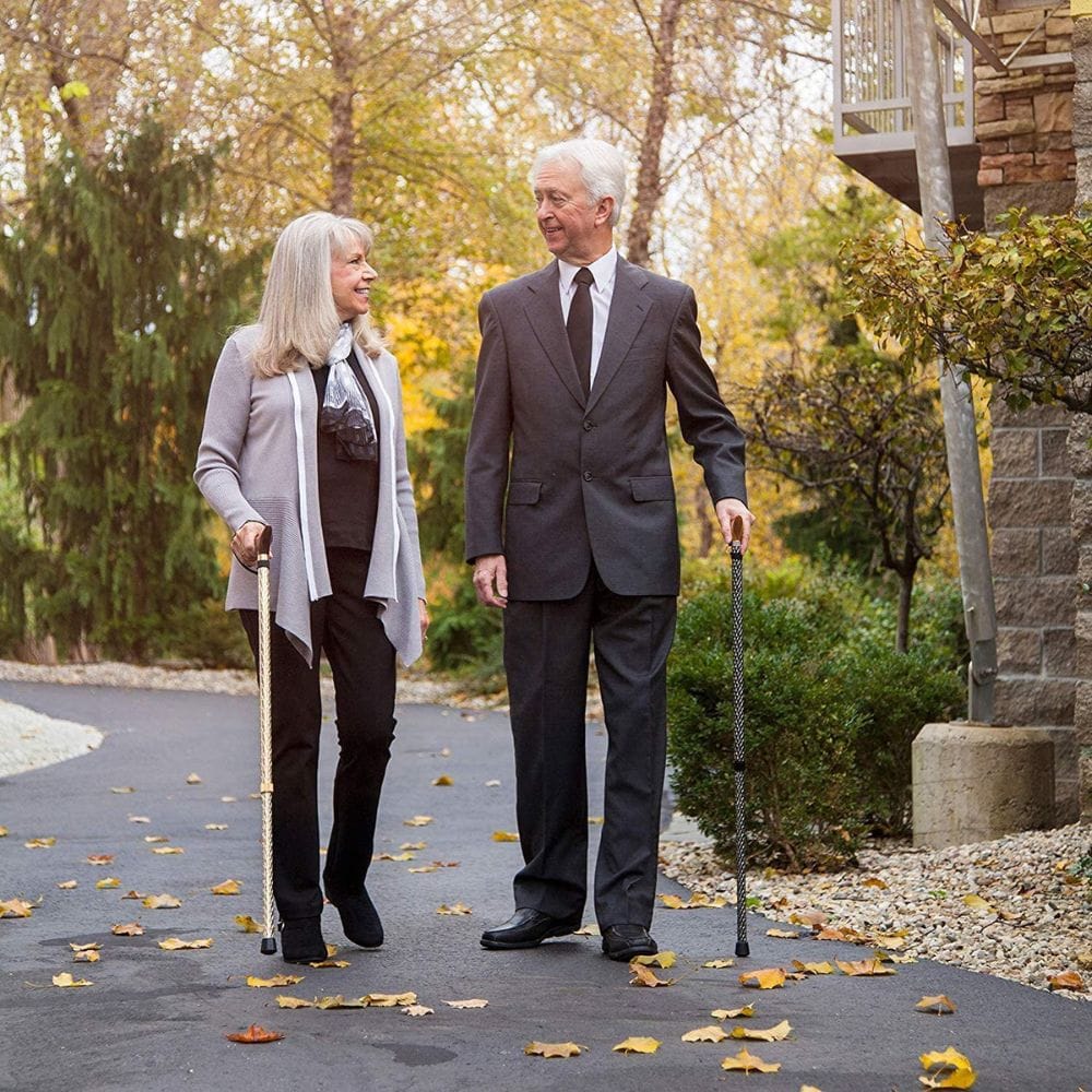 Man and woman walking together on a path with autumn leaves, holding canes.