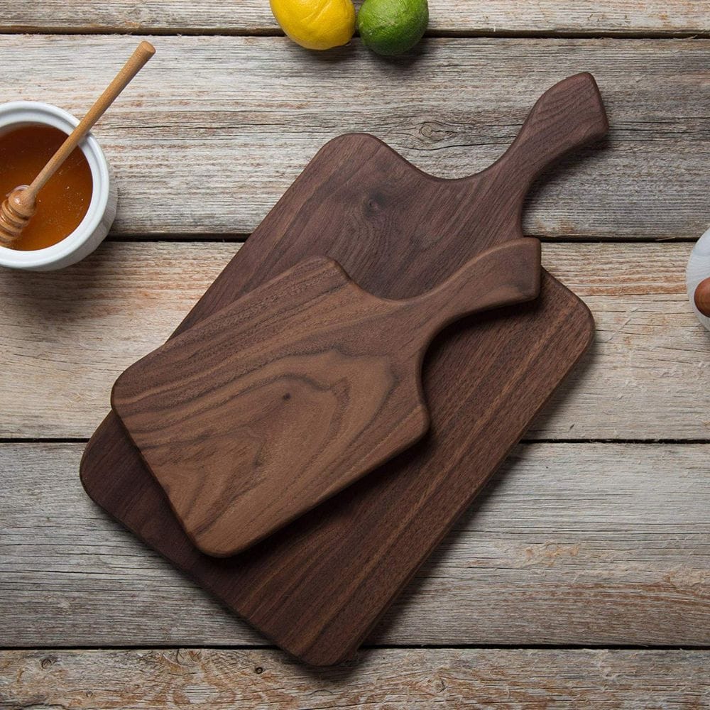 Two wooden cutting boards on a rustic wooden surface with a bowl of honey and fruits.