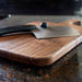 Wooden cutting board with a knife on a dark surface
