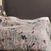 Floral patterned comforter on a bed with a dark headboard and nightstand.