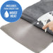 Gray heating pad with a foam insert for moist heat, being sprayed by a hand.