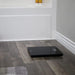 Black digital scale on a wooden floor with a neutral wall background
