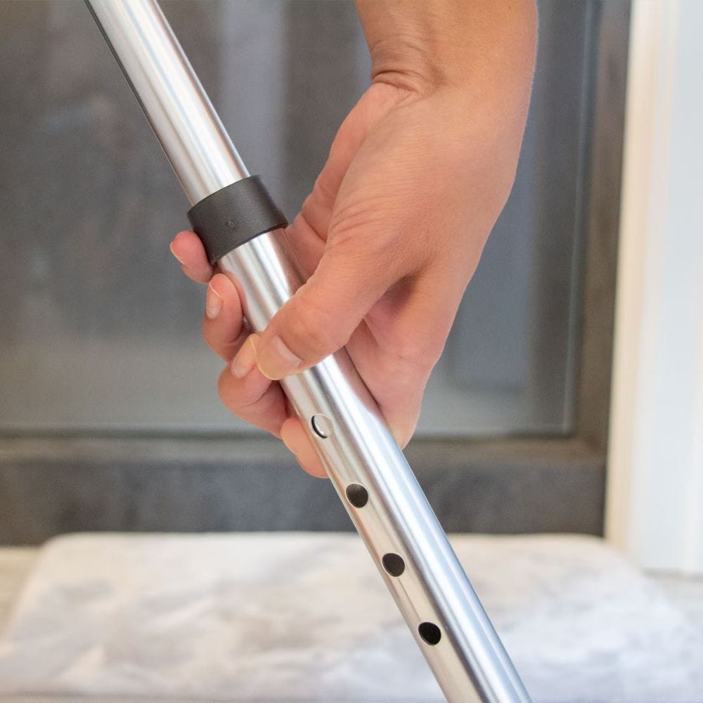 Hand holding a metal rod with a black band against a neutral background