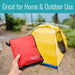 Red pouch with a logo held in front of a yellow tent outdoors.