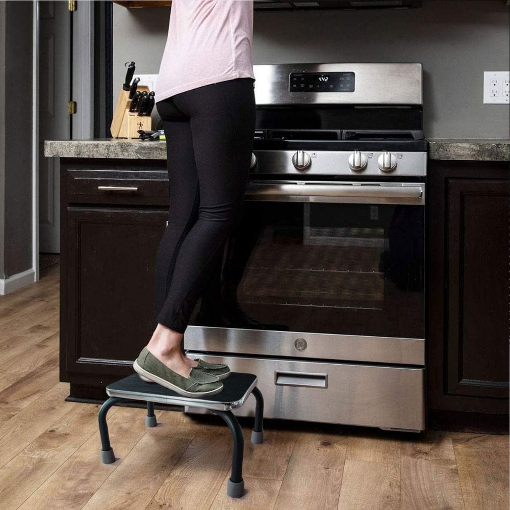 Person using a step stool to reach an oven in a kitchen