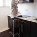 Person using a step stool to reach a high cabinet in a kitchen.