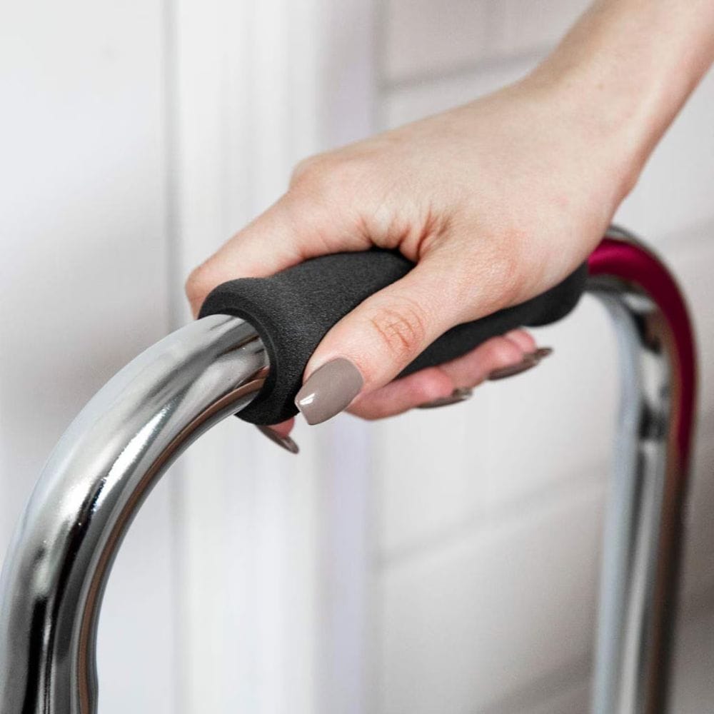 Hand holding a black grip on a metal chair handle against a white curtain background