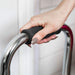 Hand holding a black grip on a metal chair handle against a white curtain background
