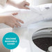 Person placing a machine washable cover on a washing machine, with a focus on the cover and washing machine.