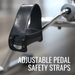 Adjustable pedal safety strap attached to a bicycle pedal with a blurred background.