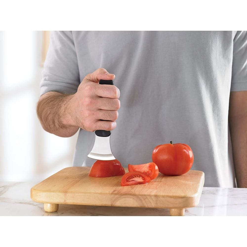 Person using a tomato peeler on a wooden cutting board with tomatoes
