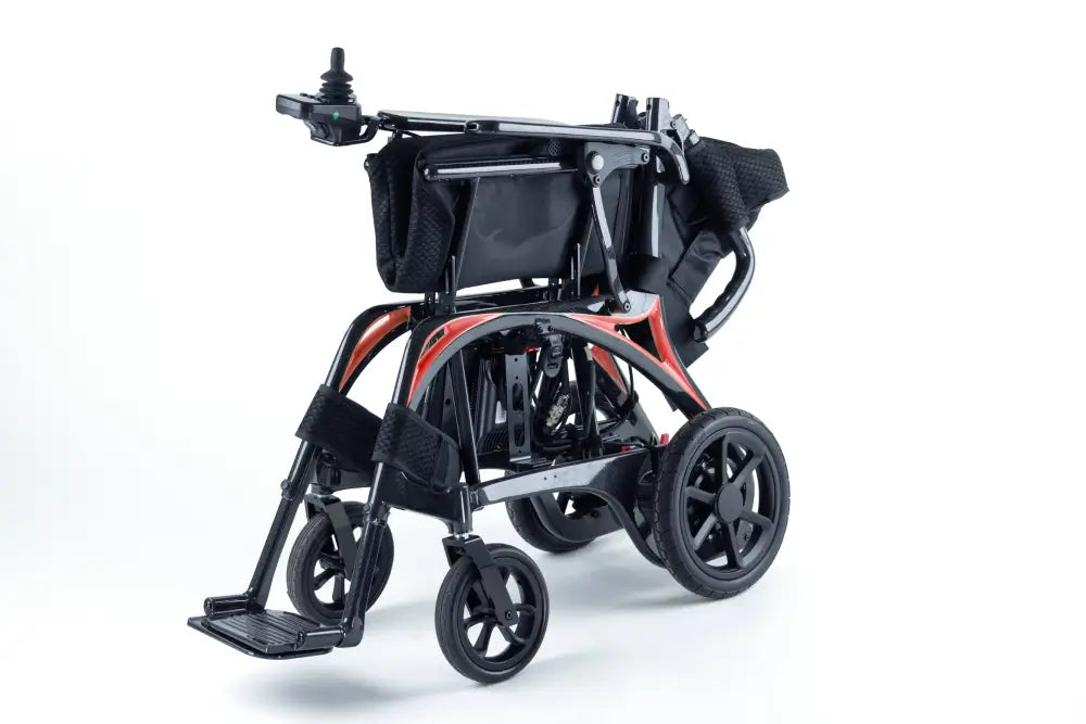 Monarch Mobility Ezi-Fold Carbon power wheelchair partially folded, showing its compact design and orange frame accents.