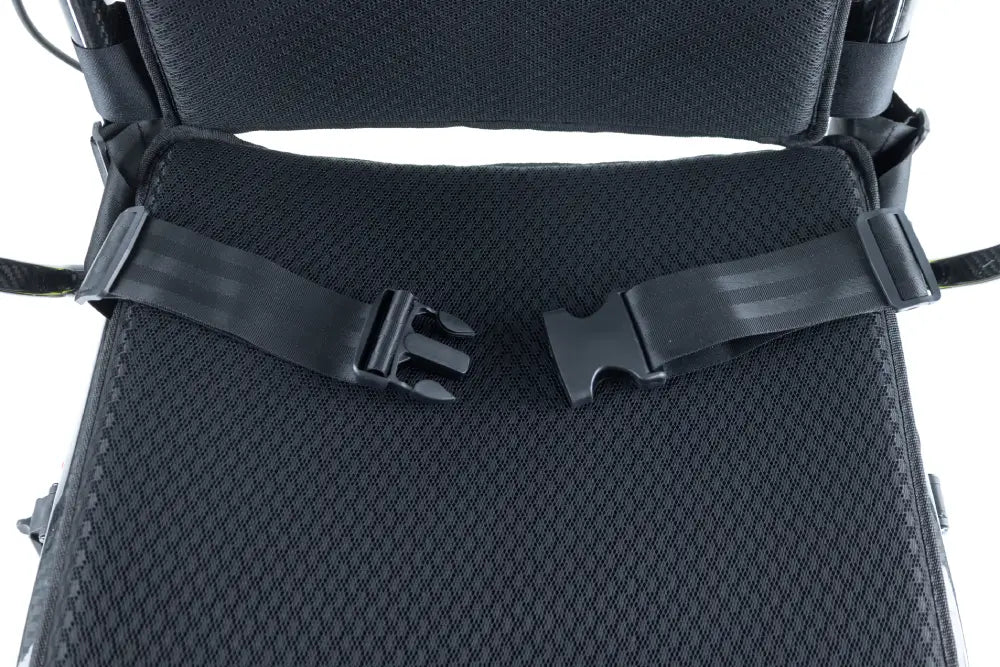 Close-up of the Monarch Mobility Ezi-Fold Carbon’s adjustable lap belt with buckle across the black mesh seat.