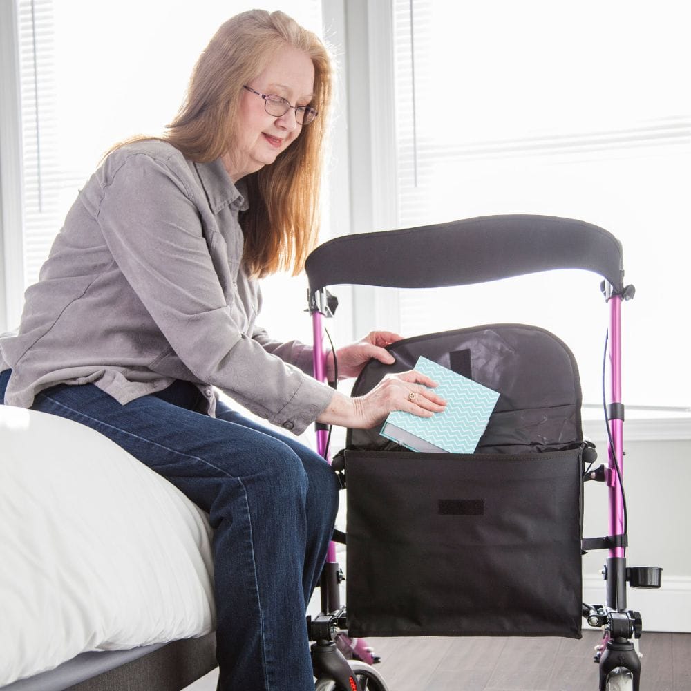 Woman using a walker with a bag attached, sitting on a bed.