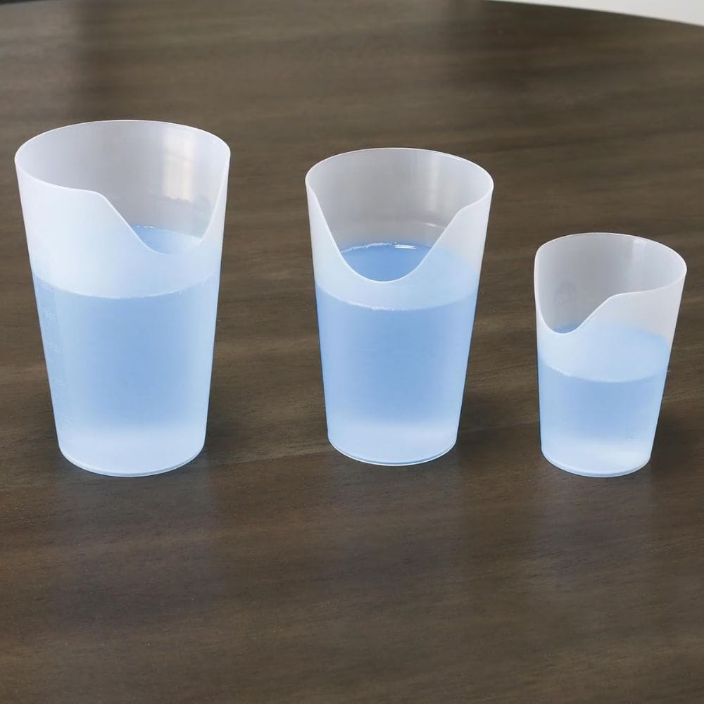 Three plastic cups with blue liquid on a wooden surface