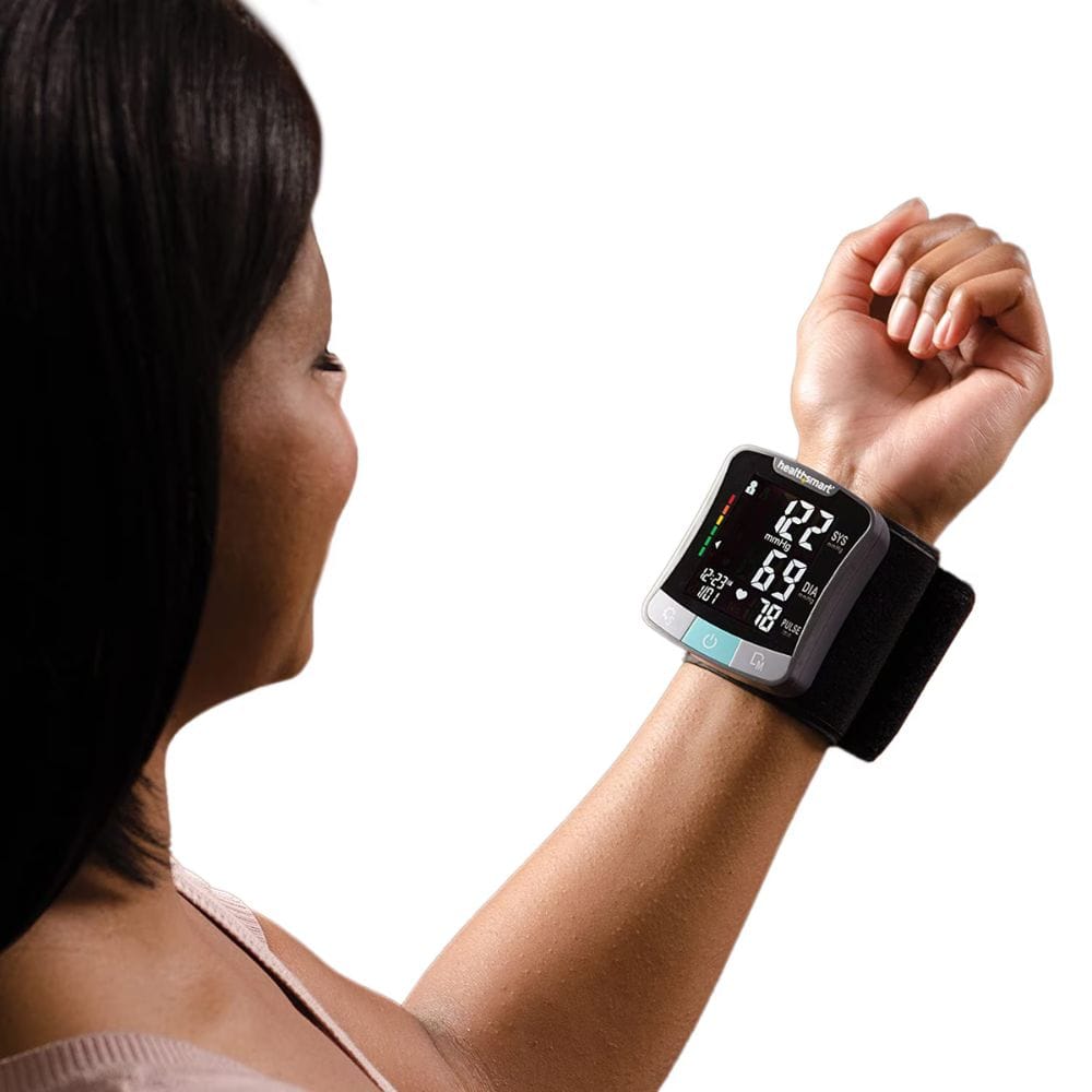 Woman using a blood pressure monitor on her wrist with a white background