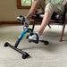 Person using a small exercise bike in a home setting
