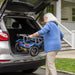 Woman loading a mobility scooter into the trunk of a car outside a house.