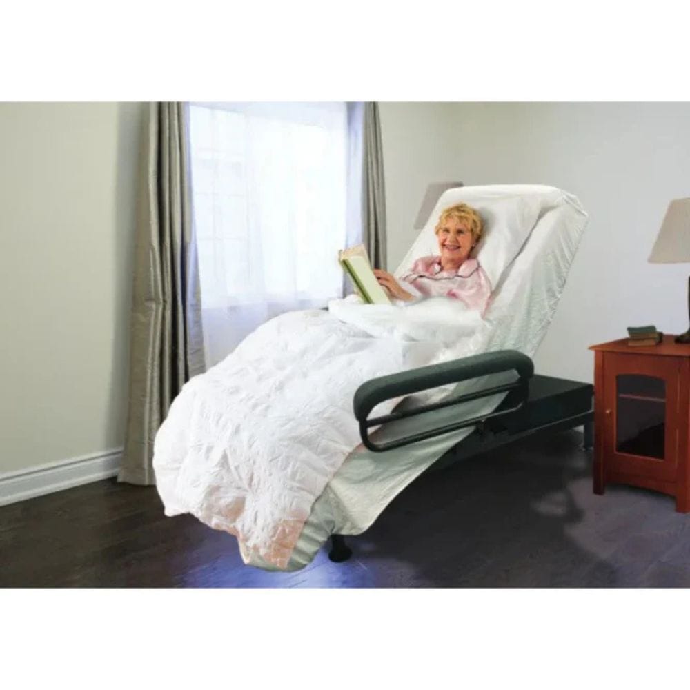 Woman reading a book in a recliner chair with white bedding in a room.