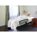 Woman lying on a bed with an adjustable footrest in a bedroom setting.