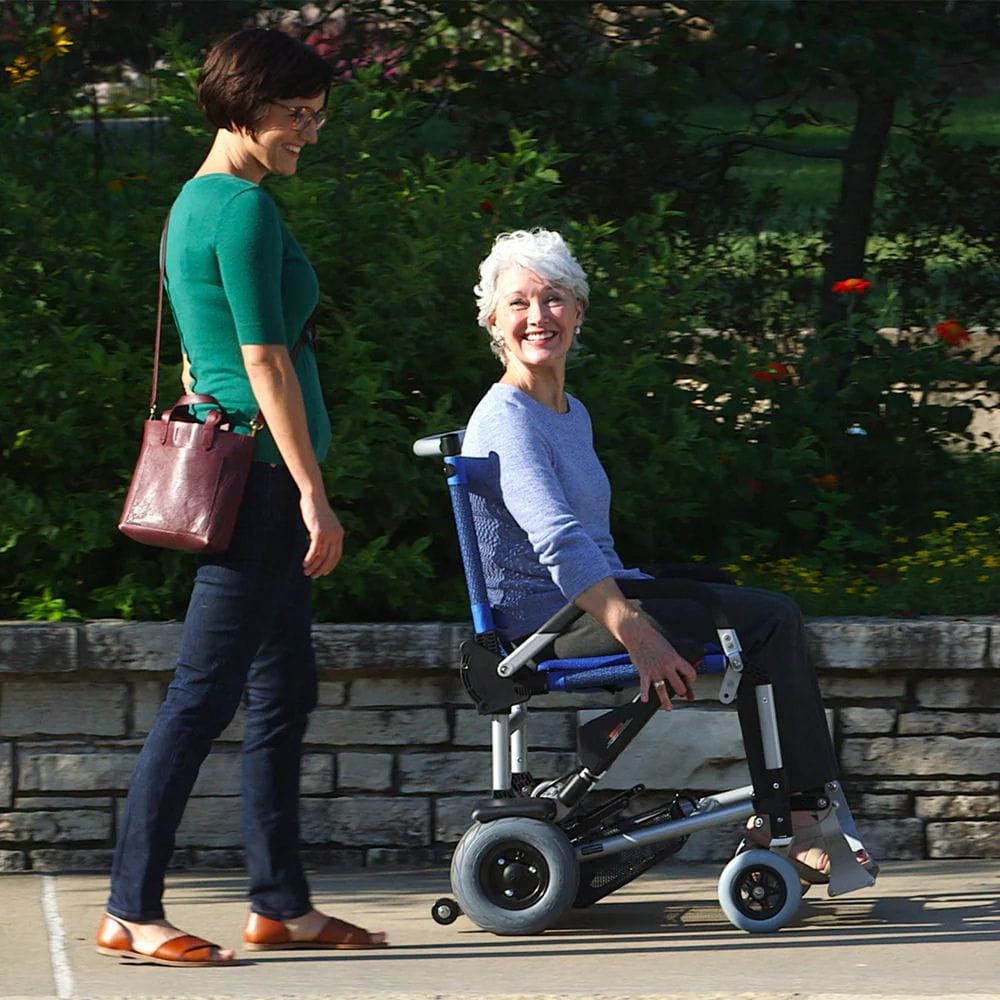 Woman pushing an elderly woman in a wheelchair outdoors.