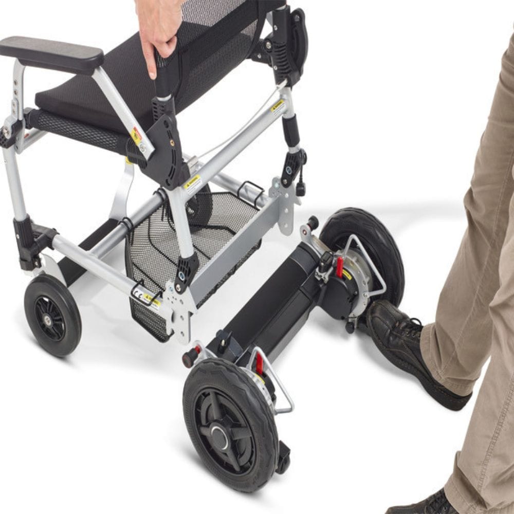 Foldable mobility scooter with a person partially visible, showing the scooter's compact design.