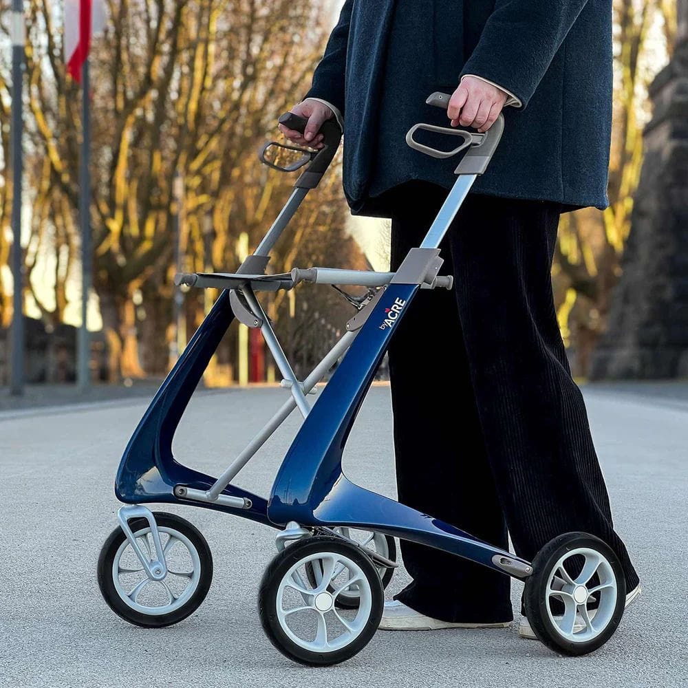 Person pushing a blue and silver rollator on a street with trees in the background