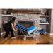 Person pushing a blue and white medical stretcher in a living room with a fireplace.