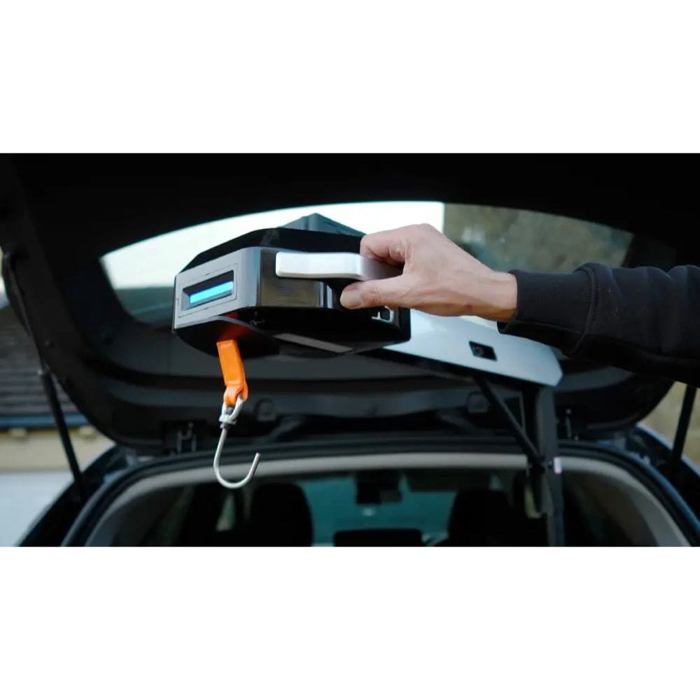 Person using a portable car jack to lift a car with an open trunk.