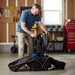 Man setting up a golf cart in a garage with tools and equipment in the background