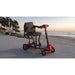 Mobility scooter on a paved path with a beach and sunset in the background