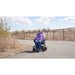 Person using a mobility scooter on a paved path with a natural landscape in the background