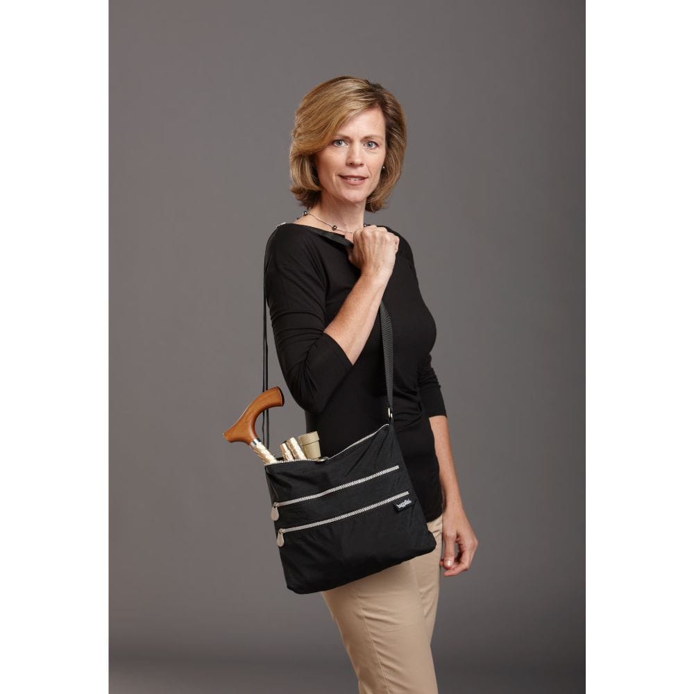 Woman holding a black bag with a wooden handle against a gray background