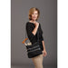 Woman holding a black bag with a wooden handle against a gray background