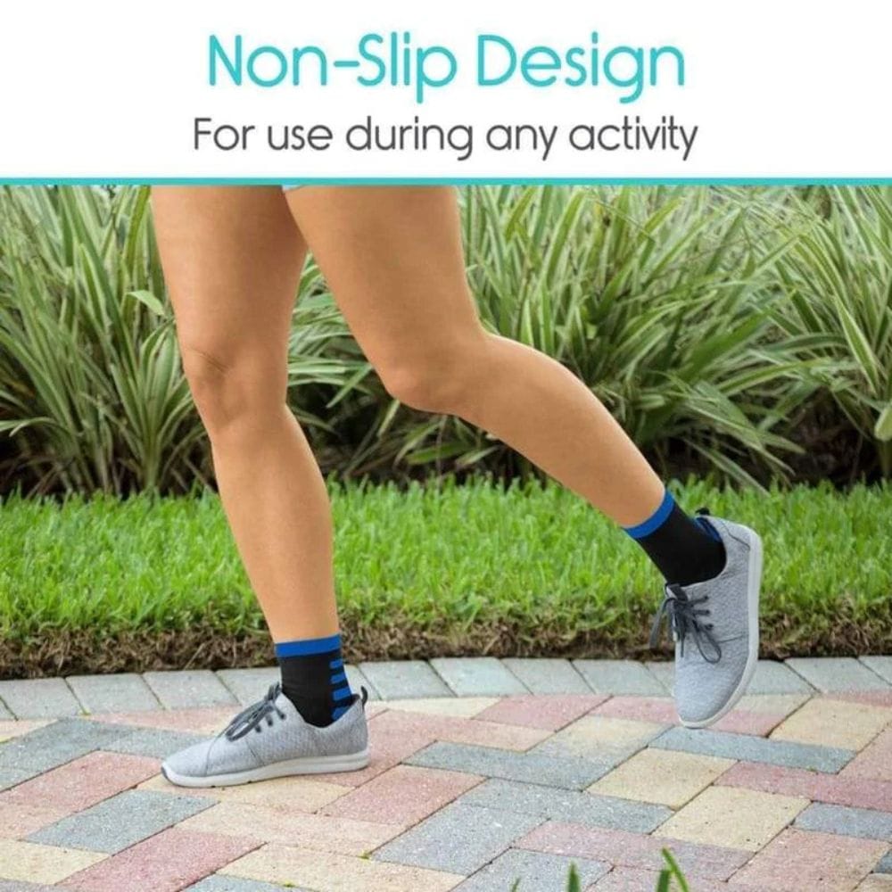 Person wearing gray sneakers with blue socks on a paved path with greenery in the background, highlighting non-slip design.