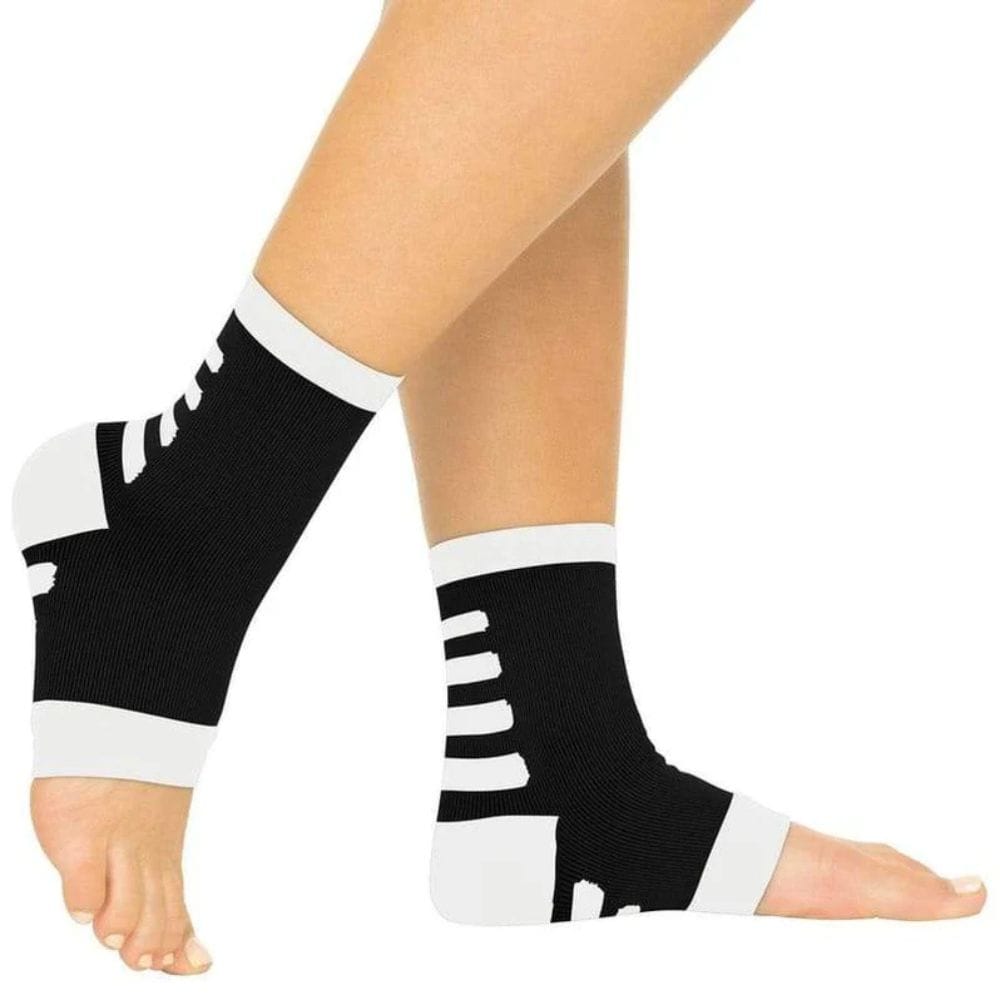 Black and white compression ankle sleeves on a person's legs against a white background