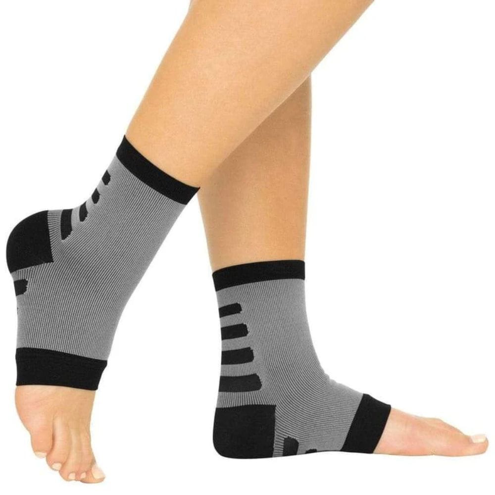 Gray and black compression socks on a person's legs against a white background