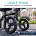 Close-up of a mobility device with large 8-inch wheels on a blurred outdoor background.