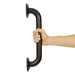 Hand holding a dark metal grab bar against a white background