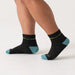 Black socks with teal accents worn by a person on a white background