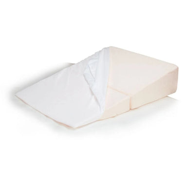 A wedge-shaped orthopedic pillow in a light peach-beige color, shown with a white fitted sheet partially pulled up on one side, set against a plain white background.